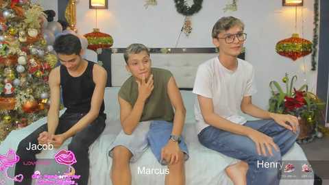 Media: Video of three young men sitting on a bed, wearing casual clothes, in a festive room with a decorated Christmas tree and red lanterns.