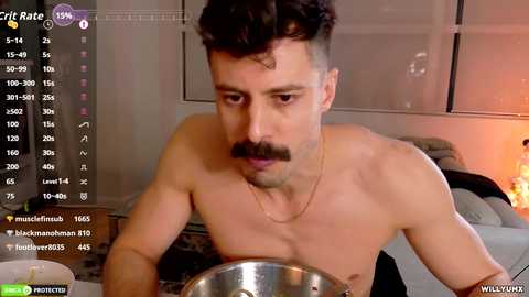 Video of a shirtless man with short dark hair, mustache, and a gold necklace, concentrating on cooking. Background includes a bed, window with blinds, and a lit candle, with live stream overlay showing viewers and chat.
