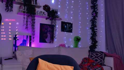 Video of a dimly lit, cozy bedroom with purple fairy lights, black and white geometric-patterned blanket, green air purifier, and a dark blue chair with a mustard-yellow cushion.