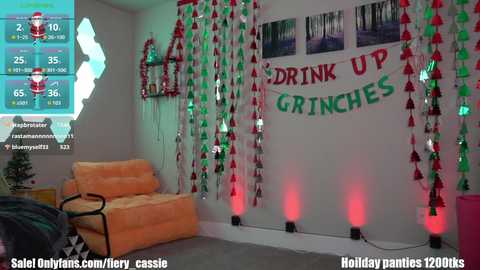 A festive, modern living room decorated with Christmas garlands, lights, and a \"Drink Up, Grinch\" banner. The room features a beige couch, a small table, and a TV displaying a game score.