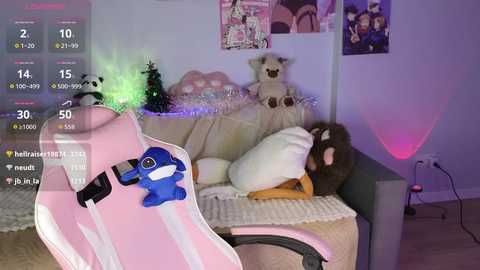 Video of a young woman in a pink gaming chair, sleeping on a beige couch with a plush toy, surrounded by Christmas decorations and posters in a cozy, dimly lit room.
