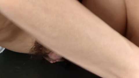 Media: Close-up video of a person's shaved pubic area with light skin tone, lying on a dark surface. The image focuses on the genital region with visible pubic hair.