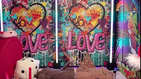 A vibrant video of a colorful, graffiti-covered backdrop with the word \"LOVE\" in bold, pink letters. A red suitcase and dice are on the left, and a person's bare chest and torso are partially visible on the right.