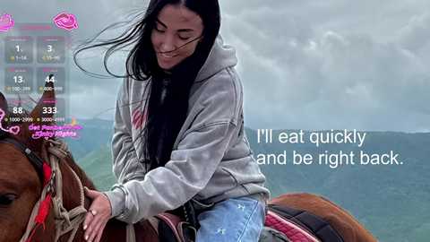A video of a smiling young woman with long black hair riding a brown horse outdoors. She wears a gray hoodie and blue jeans. Overcast sky, green mountains, and a text overlay reads, \"I'll eat quickly and be right back.\