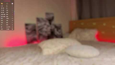 Blurry video of a bedroom with a bed, a headboard, and a wall-mounted clock with a red backlight. The room appears dimly lit, with a soft, ambient glow.