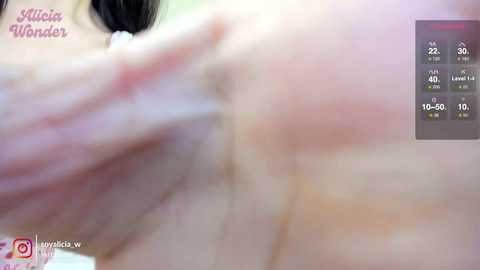 A close-up video of a woman's bare breast with pink nipples, captured in soft focus, featuring a blurred background and a digital thermometer display.