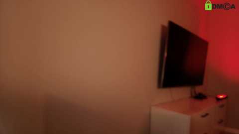 A dimly lit video of a wall-mounted flat-screen TV with a red glow, placed on a white cabinet with a red light, in a minimalist room.