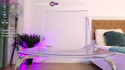 Video of a modern, clear acrylic chair in a minimalist bedroom with white walls, a beige headboard, a green pillow, and a purple light.