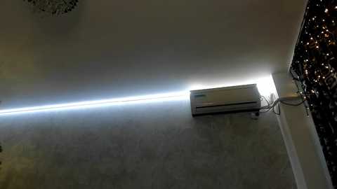 Media: Video of a minimalist interior with a sleek, horizontal air conditioner mounted on a gray, textured wall. The room features modern, clean lines and a subtle glow from the AC unit.