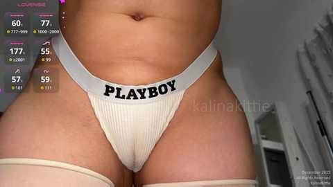 A close-up video of a person wearing white Playboy underwear with a visible, slightly rounded belly and light skin tone, taken from a low angle.