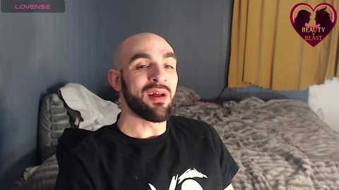Video of a bald, bearded man with a black shirt, in a gray room with a bed, yellow curtains, and \"Ready to Beast\" logo.