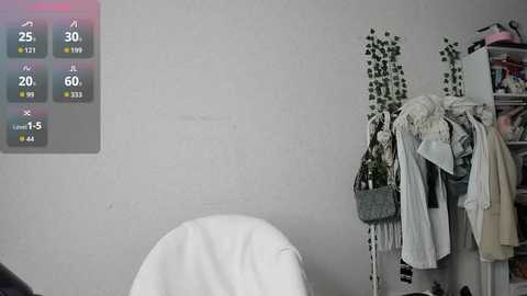 Video of a minimalist, white-walled room with a hanging plant, a white chair, and a digital thermometer showing 25\u00b0C.