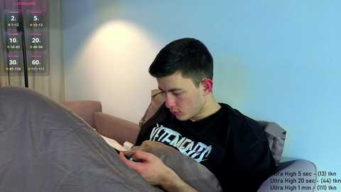 Video of a young man with short dark hair, wearing a black t-shirt, lying on a gray bed, with a visible chart indicating 30 days of sobriety.