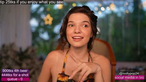 Media: Video of a young woman with light skin, brown hair, wearing a floral bikini, smiling. Background shows a blurred garden scene. Text overlays mention social media and beer consumption.