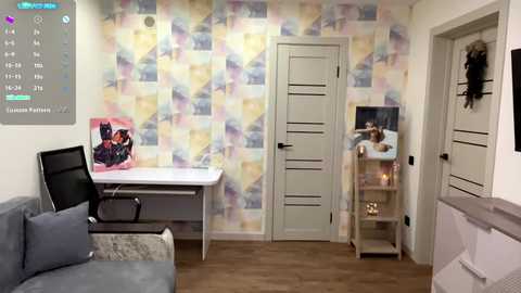 Video of a modern, pastel-colored living room with a light gray couch, a white desk, and a TV showing a Batman poster. The background features a soft, geometric-patterned wallpaper.