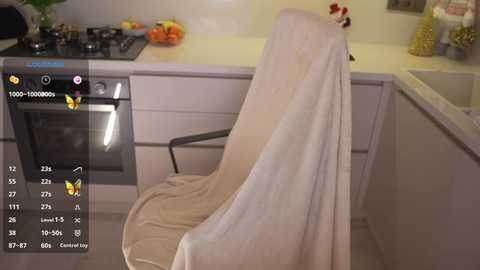 Video of a modern kitchen with a white cloth draped over a black chair, showcasing a beige tiled floor and white cabinets.