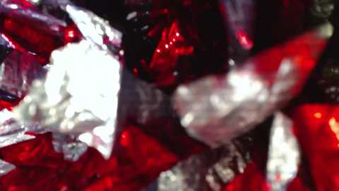 Video of a close-up, abstract view of red and white gemstones with a glossy, reflective surface, creating a vibrant and sparkling effect.