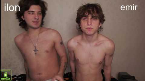 Media: Video of two shirtless young men with curly hair, tattoos, and one with a star pendant. Background is plain, with \"ion\" and \"emir\" text.