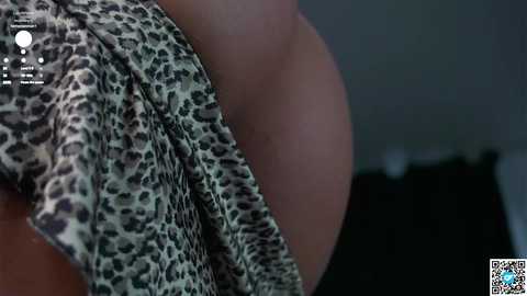 Media: Video of a close-up view of a woman's bare back, featuring a leopard-print dress, with blurred background and watermark.