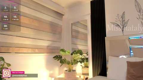 Video of a modern, minimalist living room with beige and black decor, featuring a large plant, a black radiator, and a white wall with a butterfly mural.