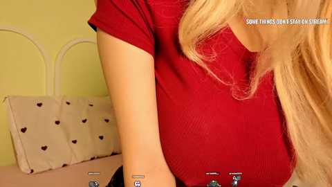 A video of a blonde woman in a red top, lying on a bed with white heart-patterned pillows, viewed from the side, with a text overlay.