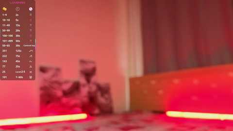 A blurred video of a room with a pinkish hue, featuring a bed with red sheets and a red curtain, and a calendar with dates and events in the top left corner.