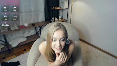 Video of a smiling, light-skinned, blonde woman in a beige armchair, with a black screen overlay showing stats like \"18/20\" and \"10-20%\" in the top left corner.