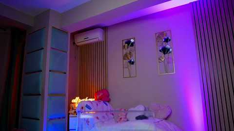 Video of a modern bedroom with purple and blue lighting, featuring a white crib with a soft blanket, wall-mounted art, and a window with vertical blinds.