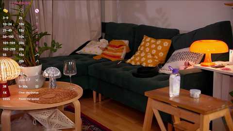 Video of a cozy living room with a dark green sectional, yellow floral cushions, wooden coffee table, and a warm, ambient light.