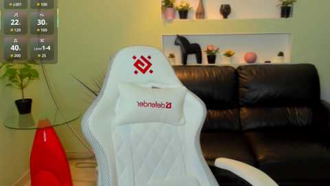 Media: Video of a modern living room with a black leather sofa, a white gaming chair, and minimalist decor, including a red plant stand and potted plants.