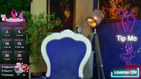 A video of a plush, blue velvet armchair with a white frame, next to a glowing lamp and a vibrant digital screen displaying \"Tip Me\" and \"Loves ON.\