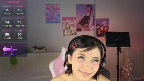 A video of a young Asian woman with short black hair, wearing headphones, smiling, in a cozy bedroom with anime posters and a green light.