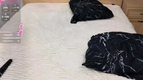 Video of a neatly made bed with white quilted sheets, black marble-patterned pillows, and a partially visible digital clock showing 2:10 AM.