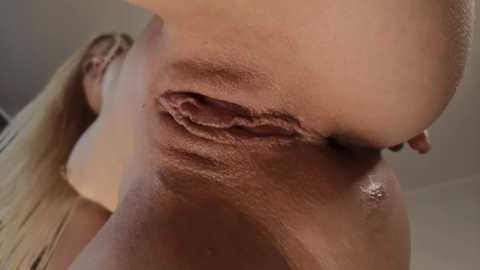 Media: A close-up, low-angle video of a nude woman's vulva and perineum, featuring light skin, visible labia, and a slightly out-of-focus background.