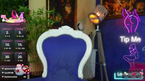 Video of a blue velvet chair with white trim, set against a purple neon \"Tip Me\" sign and a framed painting, surrounded by lush greenery and a potted plant, in a dimly lit room.
