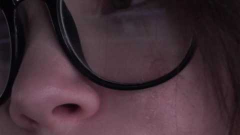 Video of a person's face with glasses, showing a close-up of the nose and glasses frame, featuring a pinkish complexion and a slightly open mouth.