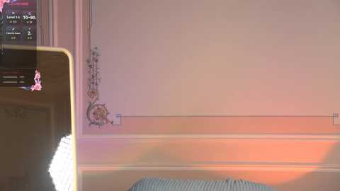 Media: A video of a cozy, softly lit room with a white wall adorned with a decorative, floral pattern. A brown chair and a window with a partially open blind are visible.