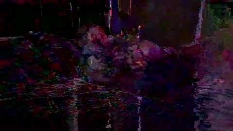 A dimly lit nighttime video of a chaotic, multi-colored explosion with debris and smoke, creating a vibrant, surreal atmosphere.