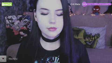 Video of a pale-skinned woman with long black hair, wearing a black choker and a black graphic tee, sleeping in a dimly lit bedroom with Batman and Spider-Man posters on the wall.