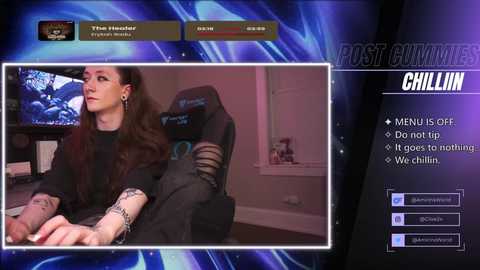 A video of a pale, tattooed woman in a black outfit, sitting in a gaming chair, viewed through a virtual reality headset.
