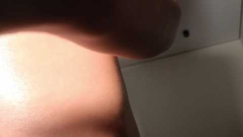 Media: A close-up video of a woman's bare, light-skinned arm and shoulder, with smooth skin and a soft, natural light illuminating the area. The background is a plain, off-white wall with a circular ceiling light fixture.