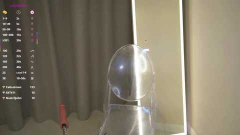 A video of a clear plastic dome-shaped object on a beige floor, with a gray curtain backdrop and a red broom handle partially visible on the left.