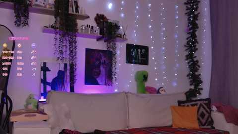 A cozy, dimly lit bedroom with a white sofa adorned with patterned cushions. The walls are adorned with fairy lights, potted plants, and framed artwork, creating a warm, inviting atmosphere.