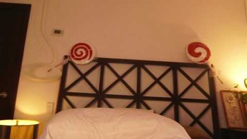 Video of a cozy, dimly lit bedroom with a wooden headboard adorned with red and white candy canes. A bedside lamp with a yellow shade casts a warm glow.