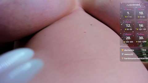 A close-up video of a woman's bare chest with a mole, showing pale skin and a blurred finger on the left. The image includes a digital overlay with a calendar and social media icons.