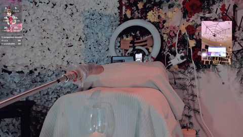 Video of a person wearing a white latex suit and holding a whip, standing in a room with a floral wallpaper, a circular mirror, and a small television.