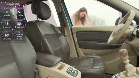 Video of a beige car interior with black leather seats, displaying a woman outside the window. Digital display shows weather forecast and temperature.