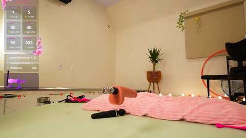 Video of a beige room with a large screen displaying a fitness game. Pink exercise mat, dumbbells, and weights on the floor. A black exercise bike and potted plant in the background.