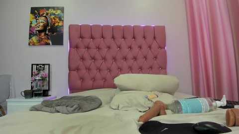A video of a messy bedroom with a pink tufted headboard, a colorful poster, and a stuffed animal on a disheveled bed.