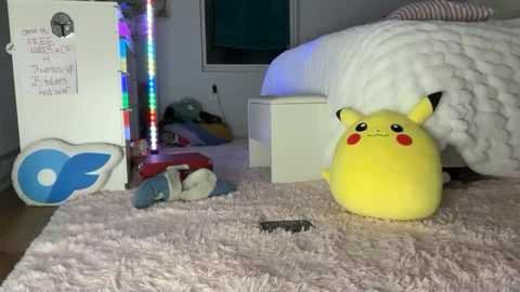 A video of a cozy bedroom with Pikachu plushies, a fluffy pink blanket, colorful LED lights, and a white bed.
